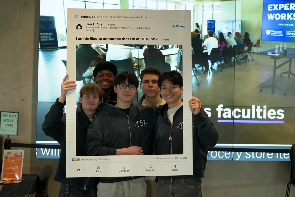 Five team members posing inside a giant cardboard LinkedIn post frame at GENESIS